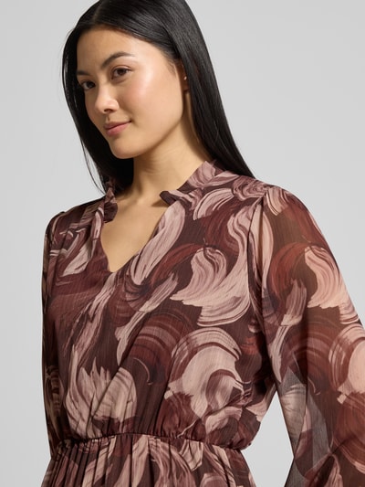 Frauenmodel trägt Midikleid mit V-Ausschnitt Modell 'Za44raa' von ZABAIONE im Stufen-Look, abstraktes Muster in Braun- und Rosétönen, transparenter Stoff, Nahaufnahme Oberkörper.