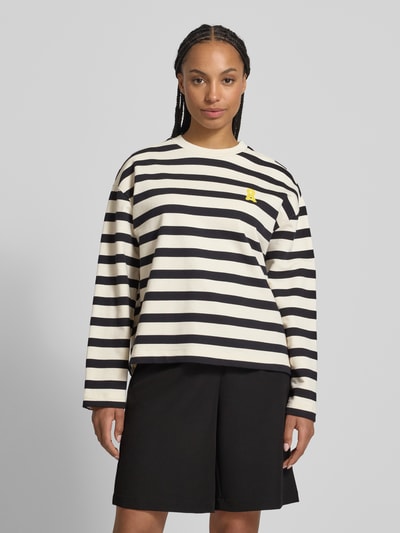 Frauenmodel trägt Oversized Sweatshirt aus reiner Baumwolle Modell 'FRANKAA BOLD' von Armedangels in Two-Tone-Optik, gestreift, Label-Patch, Logo-Stitching, Crew Neck, Rundhals, Langarm, Materialverarbeitung Sweat, Ganzkörperansicht von vorne.