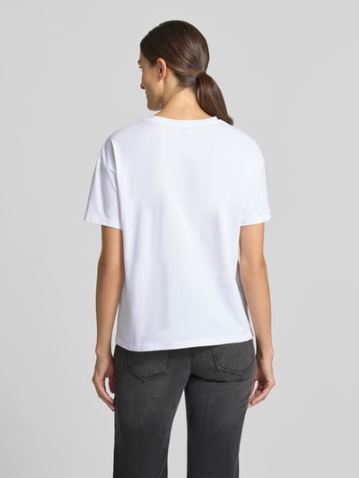 Vrouwenmodel draagt t-shirt met motiefprint en strass-steentjes van Liu Jo White, puur katoen, boxy fit, ronde hals, ruglengte maat S 60 cm, Ganzkörperansicht Rückansicht.