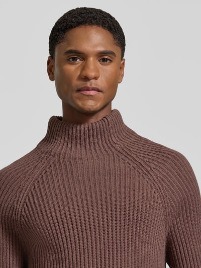 Männermodel trägt Regular Fit Strickpullover mit elastischen Abschlüssen von DRYKORN, braun, grobe Strickstruktur, Material-Mix mit Woll-Anteil, Rollkragen, Nahaufnahme Oberkörper.