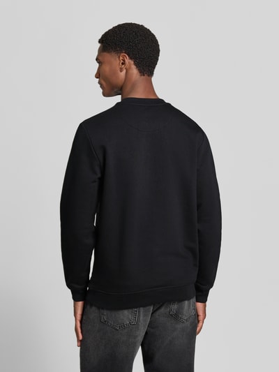 Męski model nosi Sweatshirt aus Baumwoll-Mix od MCNEAL, kolor czarny, luźny krój, wyhaftowane logo, okrągły dekolt, prążkowane wykończenia, Długość tyłu w rozmiarze M: 67 cm, Długość rękawów w rozmiarze M: 65 cm, widok całej sylwetki z tyłu.