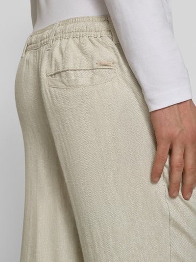 Männermodel trägt Leinenhose mit Bindegürtel Modell 'KARL MYKONOS' von Jack & Jones, cremefarben, Leinen-Viskose-Mix, Gesäßleistentasche, Relaxed-Fit, Nahaufnahme Rückansicht.