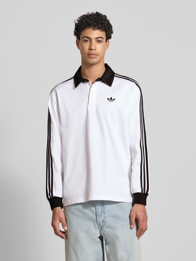 Männermodel trägt Regular Fit Longsleeve mit Logo-Stitching von adidas Originals in Weiß mit schwarzen Details, Nahaufnahme Oberkörper.
