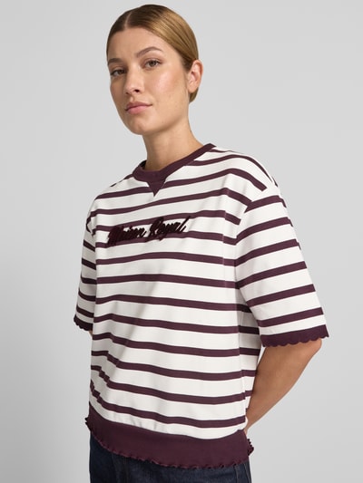Kobieta nosi Sweatshirt mit 1/2-Arm und Muschelsaum od Rich & Royal, Mieszanka bawełny z dodatkiem streczu, krój loose fit, prążkowany okrągły dekolt, detal z logo, faliste wykończenie, rękaw o dł. 1/2, widok całej sylwetki z przodu.