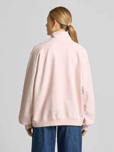 Frauenmodel trägt Oversized Sweatshirt aus reiner Baumwolle von Armedangels in Optik: Unifarben, Passform: Oversized, Label-Print, Troyer, Langarm, Raglanärmel, Materialverarbeitung: Sweat, Ganzkörperansicht Rückansicht.