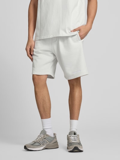 Männermodel trägt Shorts mit elastischem Bund und Logo-Stitching von Pegador aus Baumwoll-Mix, Loose-Fit, französische Eingrifftaschen, Ganzkörperansicht von vorne.