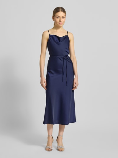 Frauenmodel trägt Slim Fit Midikleid aus Satin Modell 'Thea' von YAS in Dunkelblau mit Spaghetti-Trägern, Ganzkörperansicht von vorne. Elastischer Material-Mix, abnehmbares Taillenband, glatte Textur.