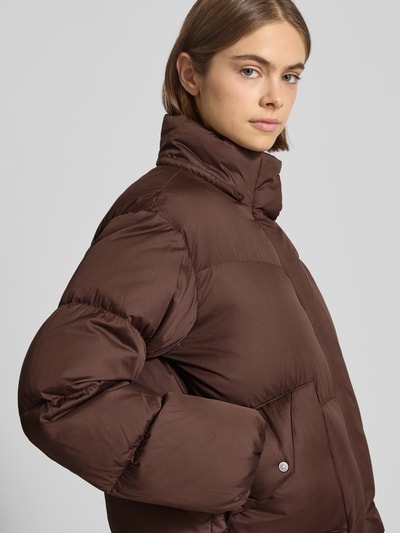 Modelka kobieca nosi brązową Regular Fit Steppjacke mit Kapuze Modell 'Bubble' od Levi's®, pikowana tekstura, kieszenie na zatrzask, zbliżenie na górną część ciała.