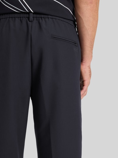Mannenmodel draagt Tapered Bundfaltenhose met halbelastischer Bund Modell 'CONVERT-PLEAT' van BOSS Green, detailopname rugaanzicht, effen donkergrijs, 4-way stretch, met persvouwen en tailleband met tunnelkoord.