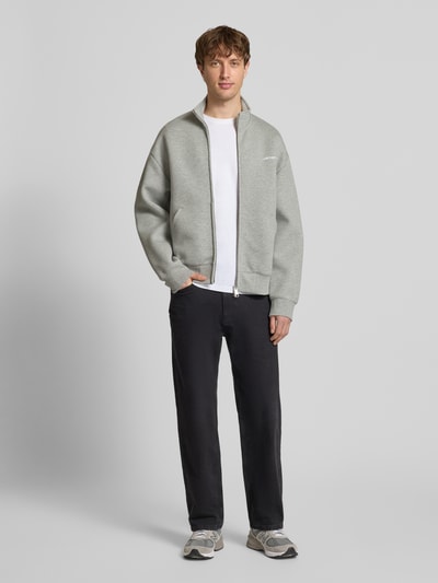 Männermodel trägt Sweatjacke mit Stehkragen von Carhartt Work In Progress in Hellgrau, legerer Schnitt, Baumwoll-Mix, Reißverschluss, Ganzkörperansicht von vorne