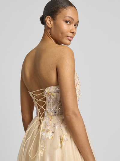Frauenmodel trägt Abendkleid mit floralem Stitching von Unique, Glitzermesh in Champagner, Pailettenbesatz, Schulterfrei, Nahaufnahme Rückansicht.