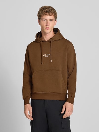 Männermodel trägt Regular Fit Hoodie aus Baumwoll-Mix Modell 'Soho' von JACK & JONES in Braun, Känguru-Tasche, Ganzkörperansicht von vorne.