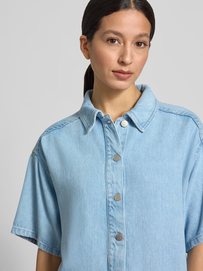 Vrouwenmodel draagt Regular Fit overhemdblouse van puur lyocell model 'Saphina' van MSCH Copenhagen in denimlook met halflange mouwen, overhemdkraag en doorlopende knoopsluiting, ruglengte maat S/M 53 cm, mouwlengte 22 cm, kleur lichtblauw, textuur glad, nahaufnahme bovenlichaam.