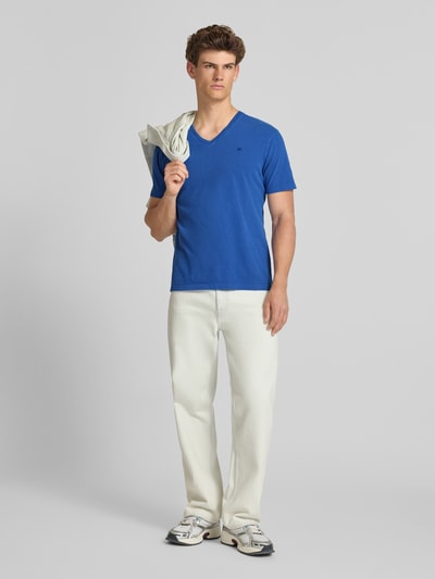 Männermodel trägt Herren T-Shirt aus Baumwoll-Leinen-Mix mit V-Ausschnitt von Superdry, Regular-Fit, mit Stitching, Rückenlänge 68 cm, Ganzkörperansicht von vorne.