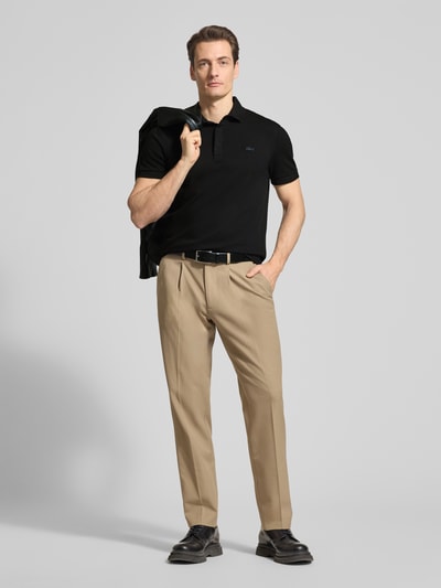 Männermodel trägt Regular Fit Poloshirt aus Baumwoll-Mix von Lacoste, efekt: jednolity kolor, krój regular fit, wyhaftowane logo, kołnierzyk polo, krótki rękaw, prążkowane zakończenie rękawów, wykończenie z rozcięciami bocznymi, pika, mieszanka bawełny; całopostaciowy widok z przodu.