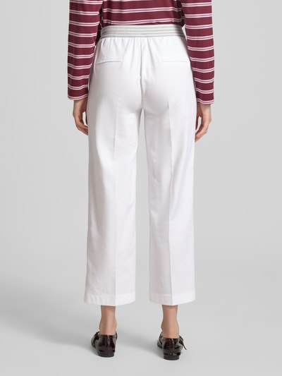 Frauenmodel trägt Wide Fit Stoffhose in 7/8-Länge Modell 'Sue' von TONI aus weißem Baumwoll-Mix mit Bügelfalten, Elastikbund und Eingrifftaschen, Ganzkörperansicht Rückansicht.