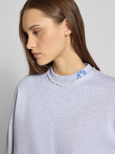 Frauenmodel trägt Oversized Sweatshirt aus reiner Baumwolle Modell 'Dismudge_B' von HUGO BLUE in Optik: Unifarben mit Logo-Stitching, Rundhals, Langarm, Material Sweat, Ärmelabschluss gerippt, Rumpfabschluss Rollsaum; Nahaufnahme Oberkörper.