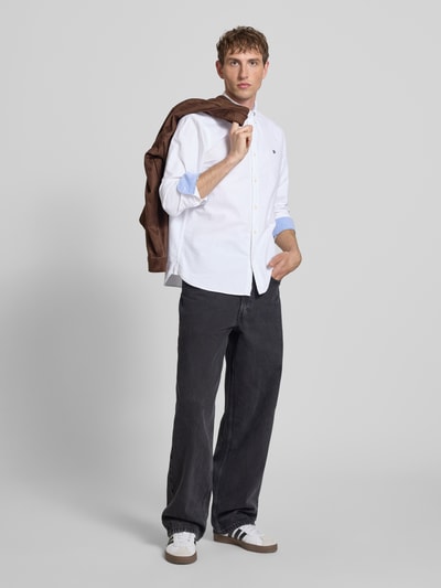 Männermodel trägt Regular Fit Freizeithemd mit Logo-Stitching von Superdry in Weiß, Reine Baumwolle, Knopfleiste, Ganzkörperansicht von vorne.