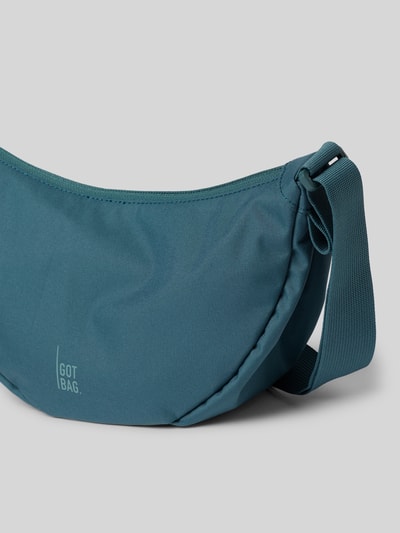 Produktfoto, Umhängetasche mit Label-Detail von Gotbag in Blau, glatte Oberfläche, verstellbarer Schulterriemen, Reißverschluss, Innenfach, Breite 31 cm, Länge 19 cm, Tiefe 9 cm, Länge Schulterriemen 87 cm.