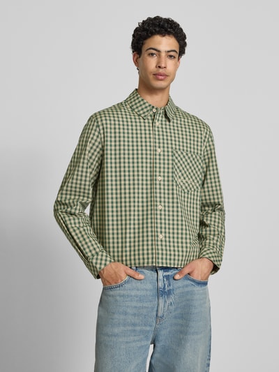 Mannenmodel draagt Boxy Fit Freizeithemd met borstzak van KARL KANI in groen-beige ruit, pure katoen, allover-look, kentkraag, label-stitching, ruglengte 63 cm, schouderbreedte 51 cm, mouwlengte 67 cm, voorkant volledig zichtbaar, bovenlichaam close-up.
