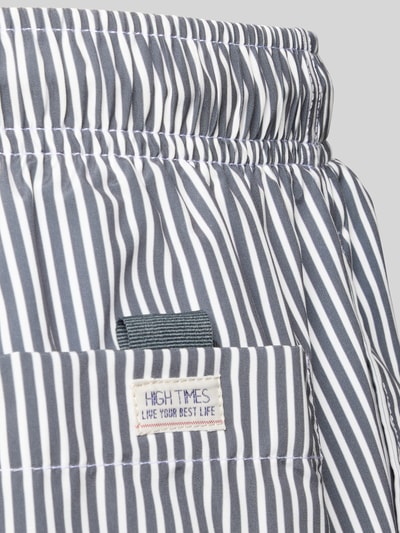 Produktfoto, Badehose mit Gesäßtasche und Label-Patch von MCNEAL mit dunkelblauen und weißen Streifen, elastischer Bund, Detailaufnahme.