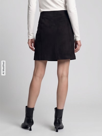 Frauenmodel trägt ausgestellten Mini-Rock mit Teilungsnähten Modell 'DONNAHAZEL' von VERO MODA in Schwarz, Ganzkörperansicht Rückansicht, Damen Mini-Rock, KI-modifiziertes Bild.