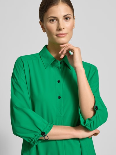 Kobiece modelka nosi knielanges Hemdblusenkleid mit Knopfleiste von Marc Cain, zielony kolor, prosty krój, detale z kołnierzem, zbliżenie na górną część ciała.
