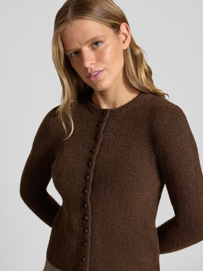 Männermodel trägt Slim Fit Strickjacke mit Woll-Anteil Modell 'Sia' von Topshop, brązowa dzianinowa faktura, krój slim fit, pełna długość rękawa, prążkowane wykończenia, długość tyłu w rozmiarze S: 50 cm, długość rękawa w rozmiarze S: 64 cm, widok na górną część ciała z przodu.