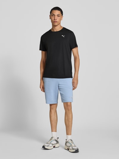Männermodel trägt Regular Fit Sport-T-Shirt mit Logo-Print Modell 'TAD Essential' von PUMA in Schwarz, Ganzkörperansicht von vorne, Herren Sport-T-Shirt von PUMA Performance.