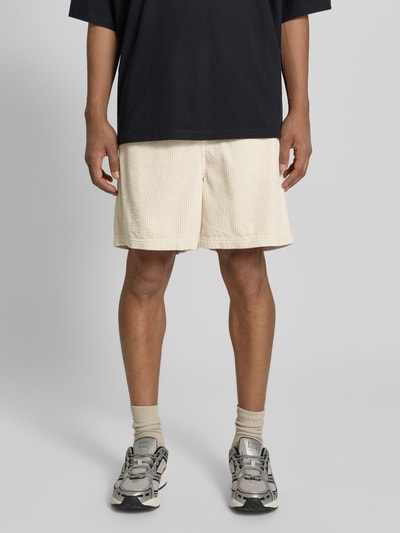 Männermodel trägt Shorts mit elastischem Bund Modell 'PADOW' von American Vintage in Beige, reine Baumwolle, Loose Fit, Ganzkörperansicht von vorne.