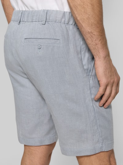 Männermodel trägt Bermudas aus reinem Leinen von JAKE*S STUDIO MEN, jasnoszary kolor, luźny krój, kieszenie, szlufki, kontrafałda, długość wewnętrzna nogawki 24 cm, szerokość w rozmiarze M 45 cm, widok z tyłu.