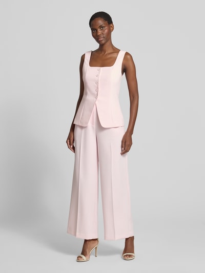 Frauenmodel trägt Wide Leg Hose mit Bügelfalten Modell 'Lee' von Forever New in zartem Rosa, Material-Mix mit Viskose-Anteil, Ganzkörperansicht von vorne.