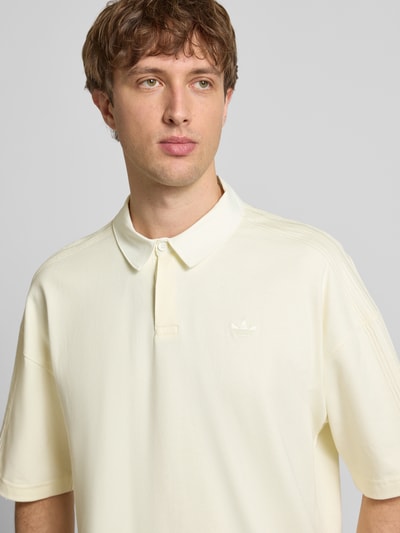Männermodel trägt Regular Fit T-Shirt mit Polo-Kragen von adidas Originals in Creme, reine Baumwolle, Logo-Stitching, Nahaufnahme Oberkörper