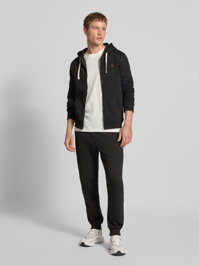 Männermodel trägt schwarze Sweatpants mit elastischem Bund von REVIEW aus Baumwoll-Mix, Slim Fit, Tunnelzug, Ganzkörperansicht von vorne.