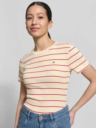 Frauenmodel trägt Slim Fit T-Shirt aus reiner Baumwolle von Tommy Hilfiger, Optik: Unifarben mit Logo-Stitching, kurzarm, Rundhals, Jersey, Ganzkörperansicht von vorne.