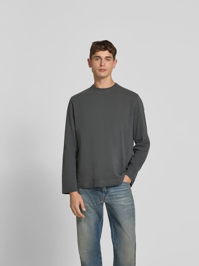 Männermodel trägt Relaxed Fit Longsleeve aus Baumwolle von Forét in Grau mit Used-Look und Label-Stitching, Ganzkörperansicht von vorne. Rückenlänge bei Größe M: 71 cm, Herren Longsleeve, Rundhalsausschnitt, Reine Baumwolle.