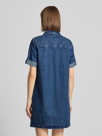 Frauenmodel trägt Jeanskleid mit Brusttaschen Modell 'NEW SIGNE' von Noisy May, Reine Baumwolle, Gerader-Schnitt, Minikleid, Hemdblusenkragen, Ärmel mit Aufschlag, Rückenlänge Größe S: 87 cm, Brustweite 49 cm, Ärmellänge 24 cm, dunkles Denim, glatte Textur, Ganzkörperansicht Rückansicht.