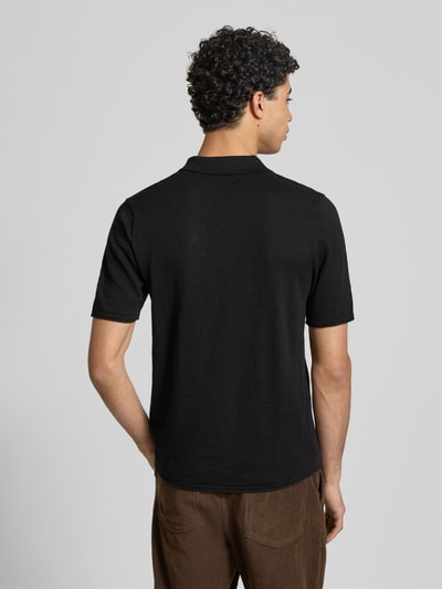 Männermodel trägt Slim Fit Poloshirt in Strick-Optik Modell 'Kane' von JACK & JONES aus reiner Baumwolle, Ganzkörperansicht Rückansicht.