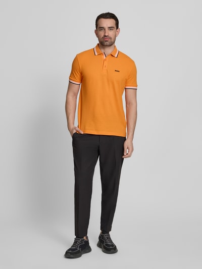 Männermodel trägt Regular Fit Poloshirt aus reiner Baumwolle Modell 'PADDY' von BOSS Green, Optik: Unifarben, Label-Print, Ganzkörperansicht von vorne.