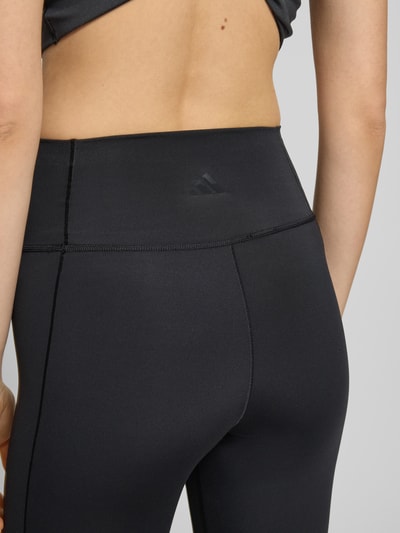 Frauenmodel trägt Flared Fit Stoffhose mit breitem Bund Modell 'All Me' von adidas Sportswear in Schwarz, elastischer Material-Mix, Nahaufnahme Rückenansicht.