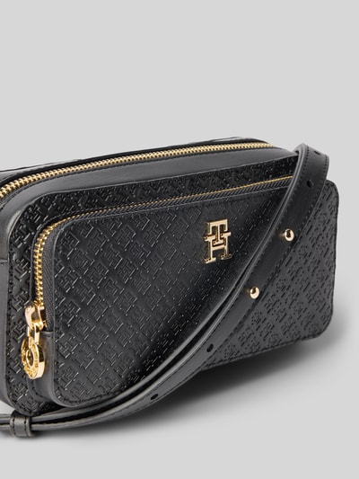 Produktfoto, Umhängetasche mit abnehmbarem Schulterriemen von Tommy Hilfiger in Schwarz mit Allover-Prägung, goldenen Details und Logo-Prägung, RFID-Schutz, Hauptfach und Seitenfach, glatte und strukturierte Textur