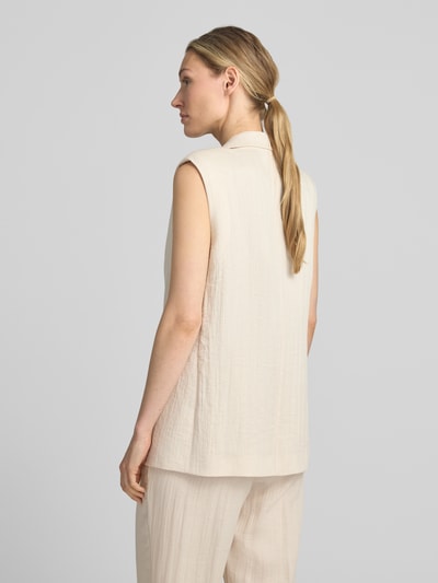 Vrouwenmodel draagt bodywarmer uit Viscosemix met reverskraag van comma, relaxed fit, steekzakken, ruglengte maat 36: 68 cm, borstwijdte 50 cm. Ganzkörperansicht Rückansicht.