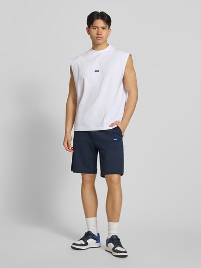 Männermodel trägt Regular Fit Sweatshorts aus reiner Baumwolle Modell 'NASENSIO' von Hugo Blue, Optik: Unifarben, Label-Patch, Tunnelzug, Bundabschluss: elastisch, seitliche Eingrifftaschen, Materialverarbeitung: Sweat, Material: reine Baumwolle, Ganzkörperansicht von vorne.