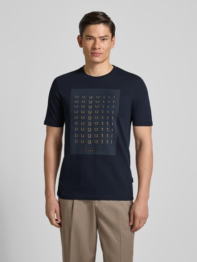 Männermodel trägt Regular Fit T-Shirt mit Logo-Print von bugatti, navy, Reine Baumwolle, Rundhalsausschnitt, Herren T-Shirt, Ganzkörperansicht von vorne. Rückenlänge bei Größe M: 70 cm.
