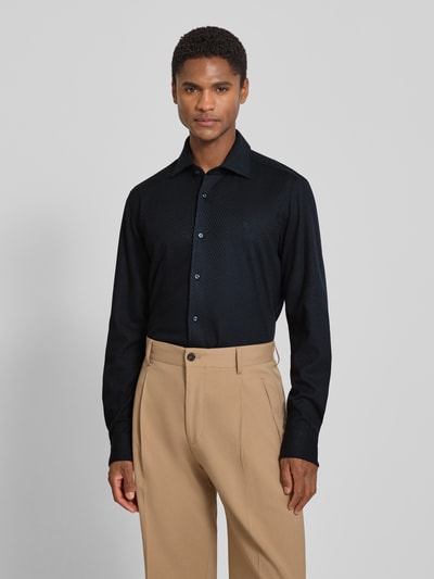 Męski model nosi Slim Fit Business-Hemd mit Haifischkragen Modell 'Phil' od JOOP! z fakturowanym wzorem z bawełny, wyhaftowane logo, czarny, krój slim fit, kolekcja, Ganzkörperansicht z przodu. Długość tyłu w rozmiarze 40: 80 cm, szerokość ramion w rozmiarze 40: 42 cm, długość rękawów w rozmiarze 40: 72 cm.
