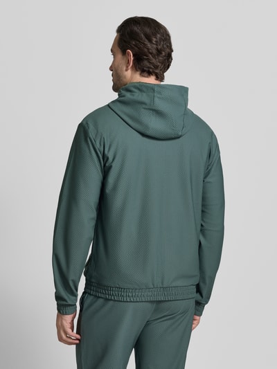 Männermodel trägt Regular Fit Sweatjacke mit Logo-Patch von EA7 Emporio Armani in Grün mit Strukturmuster, Kapuze, Ganzkörperansicht Rückansicht. 

Kontext: Herren Sweatjacke von EA7 Emporio Armani mit Elastischer-Material-Mix, Regular-Fit, Logo-Patch, Kapuze mit Tunnelzug, Strukturmuster, Eingrifftaschen, Zweiwege-Reißverschluss und elastischen Abschlüssen, Rückenlänge bei Größe M 68 cm, Ärmellänge 67 cm.
