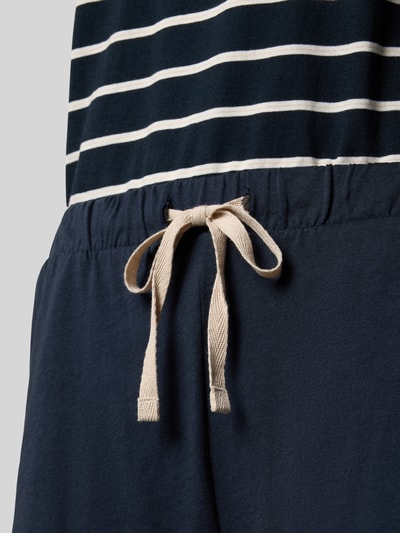 Frauenmodel trägt Regular Fit Pyjama-Set aus reiner Baumwolle von Marc O'Polo, Oberteil gestreift, Hose uni mit elastischem Bund und Tunnelzug, Jersey-Material, Nahaufnahme Taillenbereich.