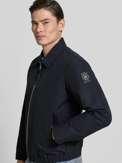 Männermodel trägt Regular Fit Blouson mit Label Patch - Marc O'Polo × DFB Travel Collection, Optik: Unifarben, Material: Baumwoll-Mix, Nahaufnahme Oberkörper.