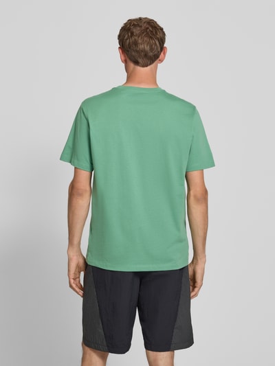 Männermodel trägt T-Shirt mit Label-Stitching und Rundhalsausschnitt von The North Face, Herren T-Shirt aus Baumwoll-Mix, Regular-Fit, Rückenlänge bei Größe M 72 cm, grün mit glatter Textur, Ganzkörperansicht Rückansicht.