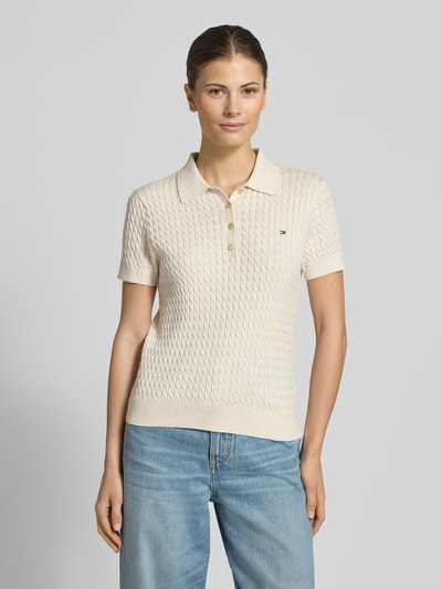 Vrouwenmodel draagt Slim Fit Poloshirt aus reiner Baumwolle van Tommy Hilfiger, look: effen, kabelpatroon, logodetail, puur katoen, knitwear, korte mouw, polokraag, v-hals, knoopsluiting, mouwboord, rompzoom, voorkant bovenlichaam close-up.